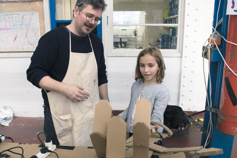 A girl and a man building a cardboard arm