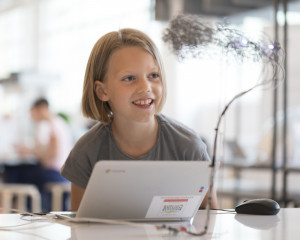 A girl with a laptop connected to a wire sculpture